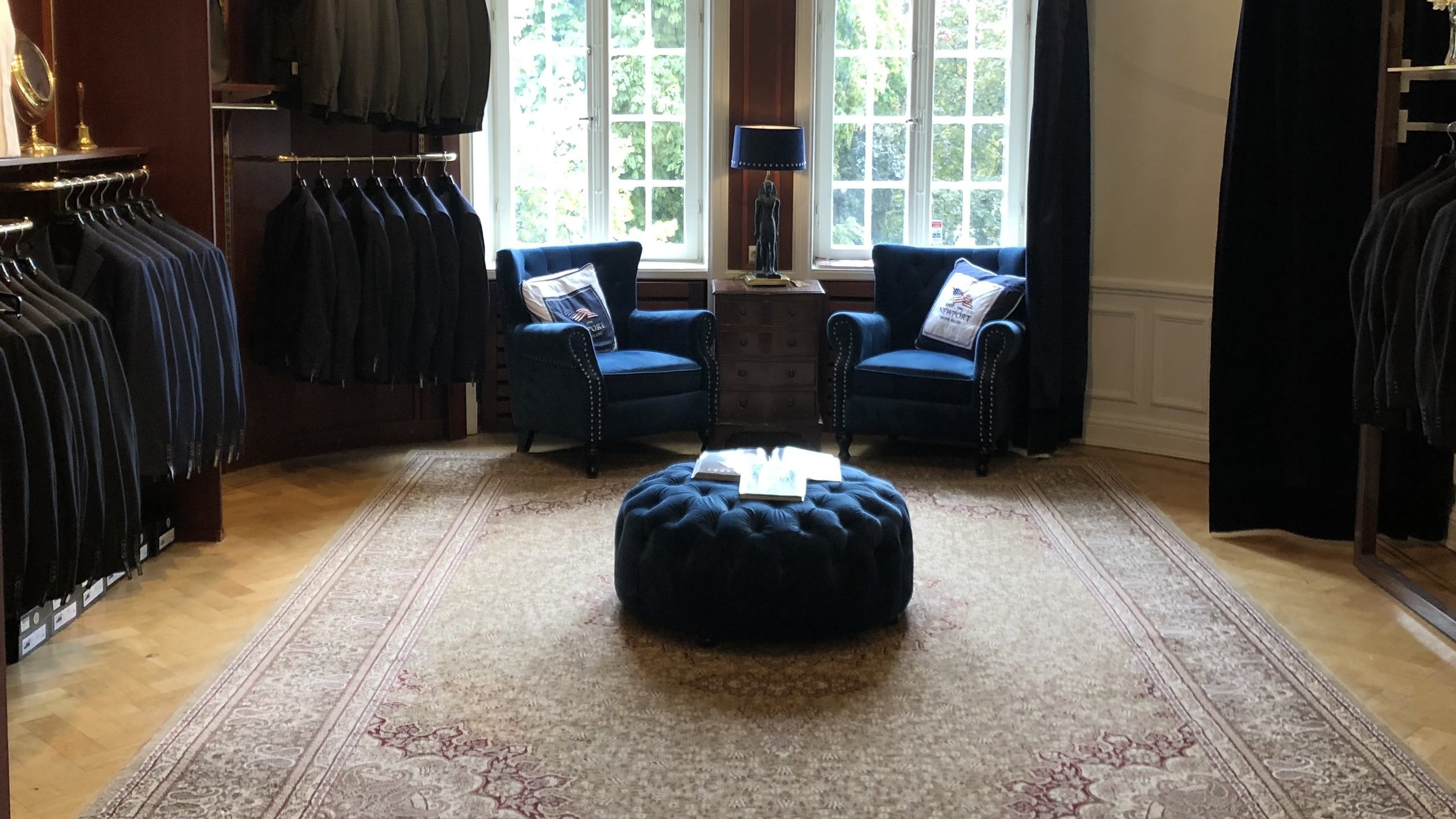 Provrummet hos House of Steens med blå fåtöljer, orientalisk matta och kostymer på rad